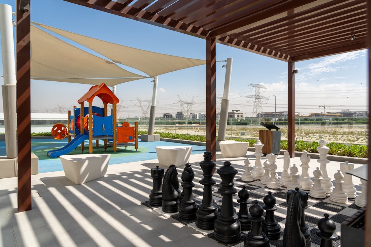 Vibrant outdoor playground with a giant chess set under shade in Dubai.